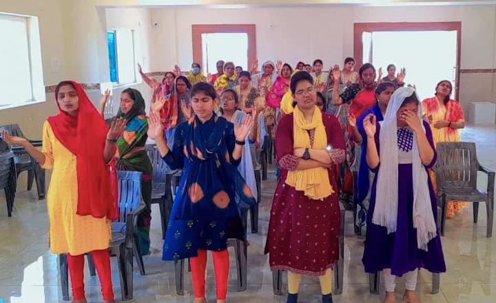 Women and girls of the congregation standing with hands raised in worship