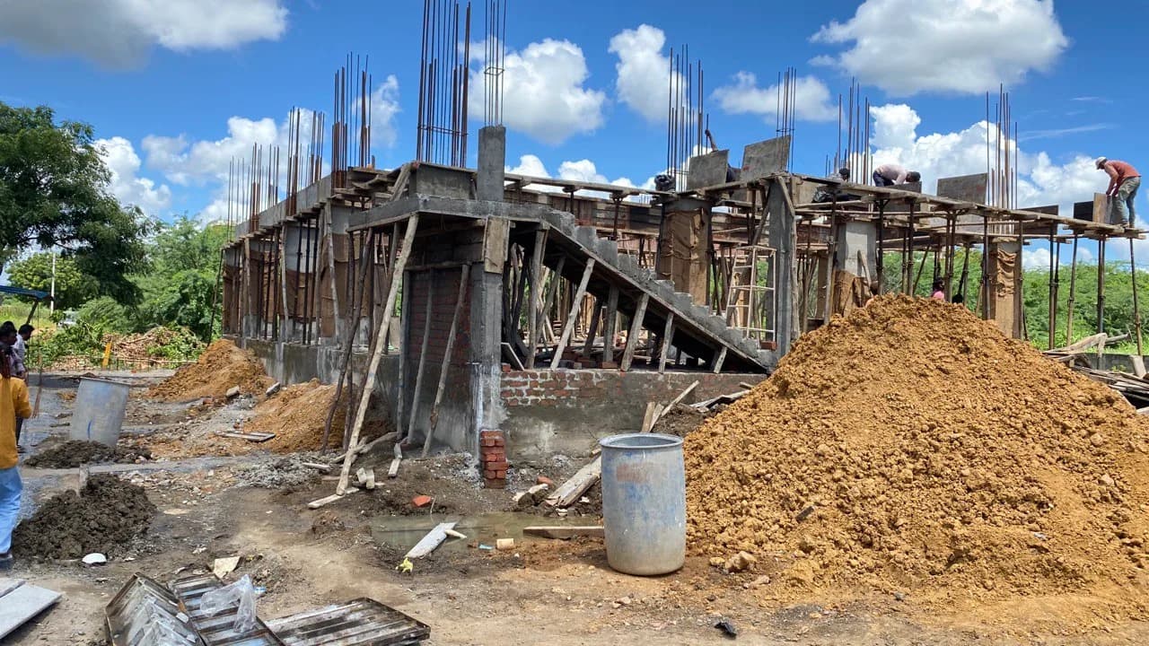 Concrete columns in timber formwork rising above the foundation, with building materials on site