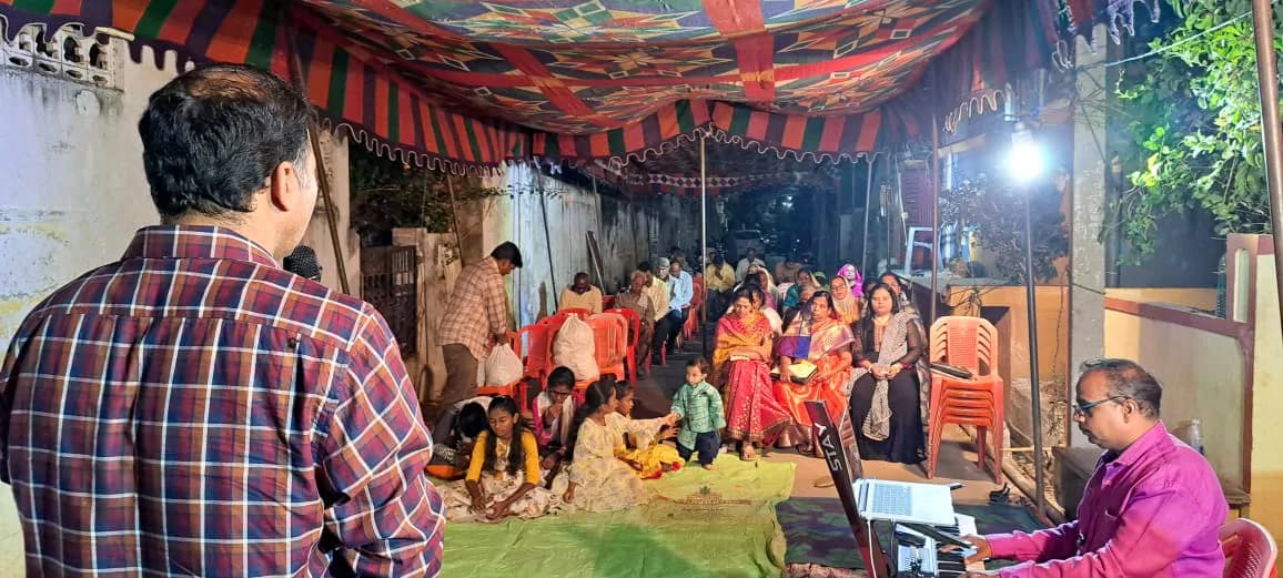 An evening gathering under a decorated canopy, with the congregation seated together