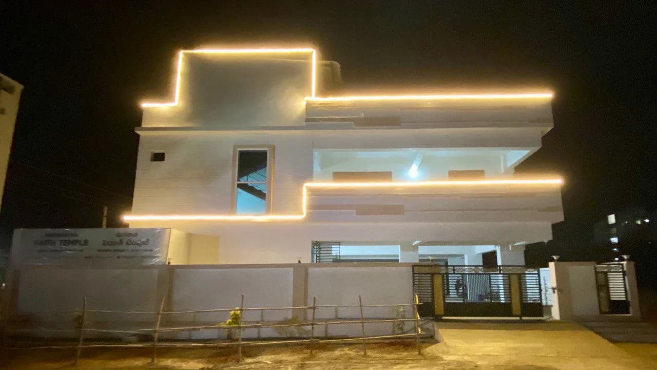 The church building at night with its roofline outlined in warm light